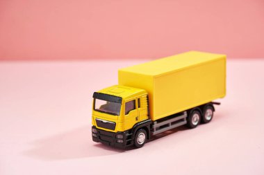 Sarı oyuncak kargo kamyonu yine pembe arka plan                       