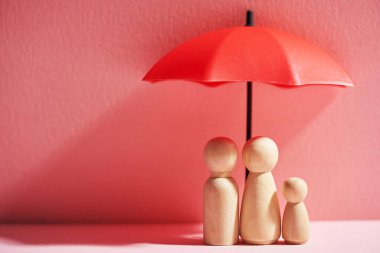 Şemsiye ve fotokopi alanı olan tahta bebekler. Aile koruması ve sigorta sigortası kavramı.           