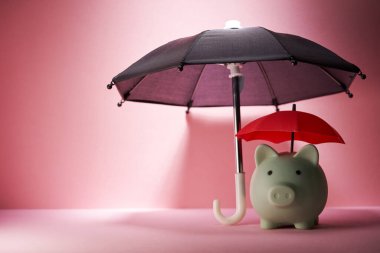 Piggybank ve pembe arka plana karşı iki şemsiye - çifte koruma