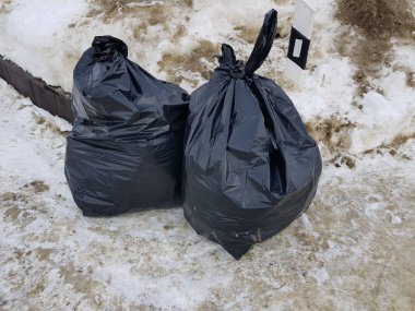 Çöp ve kışın kar üzerinde dağınık çöp torbaları