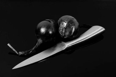 soğan, mavi soğan ve keskin bir bıçak bir siyah ayna masada yansıtılır