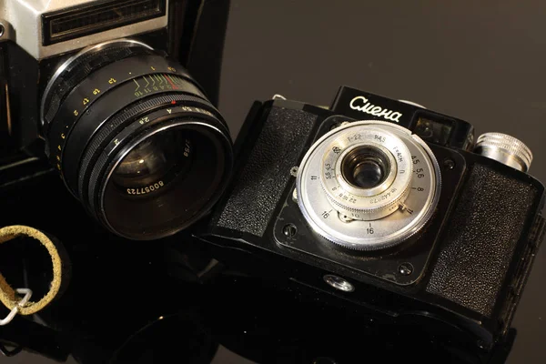 几台老式相机反射在一张黑色的镜子桌子上 — 图库照片