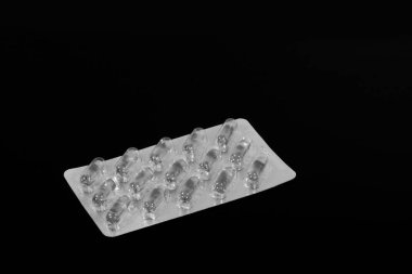 hap ve balık yağı kapsülleri bir paket içinde bir siyah ayna masada yansıtılır