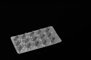 hap ve balık yağı kapsülleri bir paket içinde bir siyah ayna masada yansıtılır