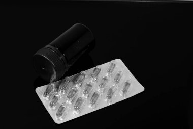 hap ve balık kapsül ve siyah ayna masada yansıyan bir paket hap bir kavanoz yağ