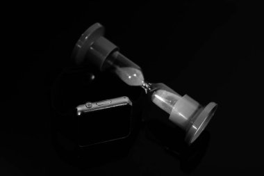 Elektronik saat ve kum saati siyah ayna masada yansıtılır