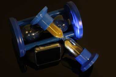 Elektronik saat ve kum saati siyah ayna masada yansıtılır