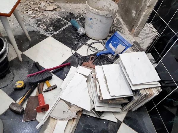 Araçlar ve çekiç, keski, cleaver, fırça, faraş ve eski fayans zemin üzerinde şerit metre ile bina onarım