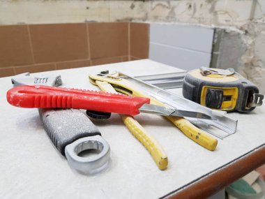 Tamir araçları anahtarı, bıçak, demir bıçak, ayarlanabilir anahtarı ve şerit metre ile bir taburede bina-