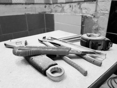 Tamir araçları anahtarı, bıçak, demir bıçak, ayarlanabilir anahtarı ve şerit metre ile bir taburede bina-