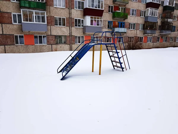 Parco giochi per bambini vicino alla casa in inverno — Foto Stock