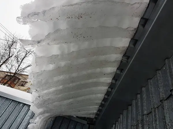 Nebezpečná ledová kostka s sněhu na střeše visí v zimě — Stock fotografie