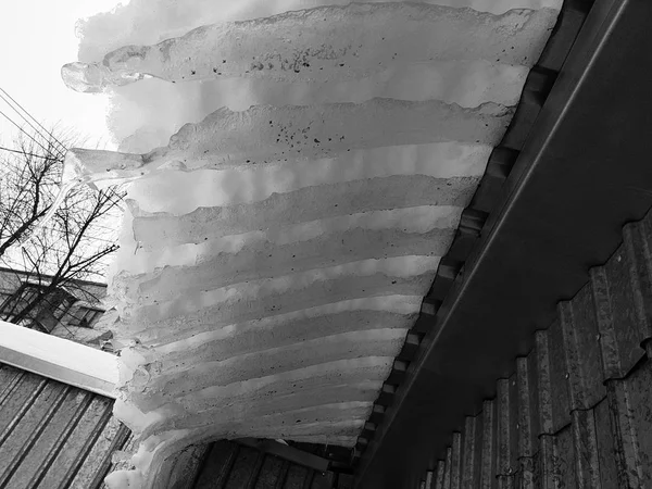 Gefährlicher Eisblock mit Schnee auf dem Dach hängt im Winter — Stockfoto