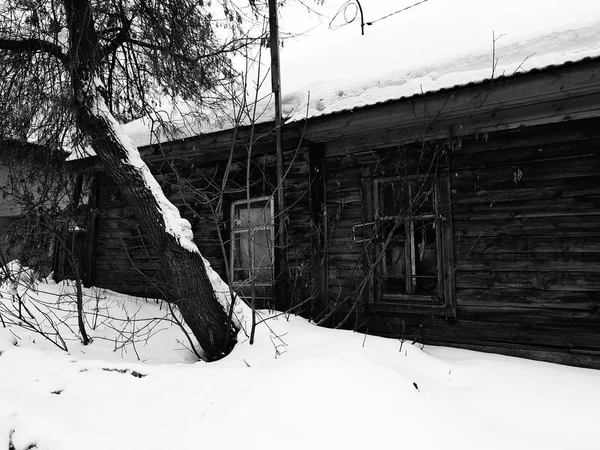 冬の雪の背景に壊れた窓と古い廃屋 — ストック写真