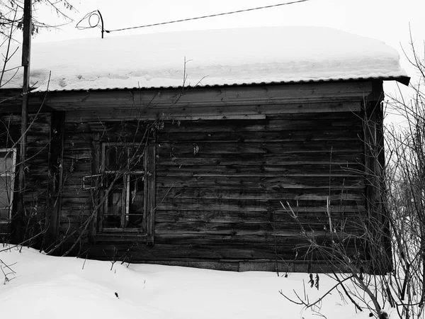 Старый заброшенный дом с разбитым окном на фоне снега зимой — стоковое фото