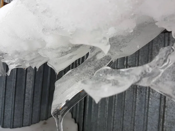 Опасный ледяной блок с снегом на крыше висит зимой — стоковое фото