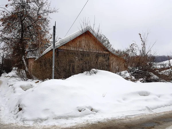 Vecchia casa abbandonata con una finestra rotta sullo sfondo della neve in inverno — Foto Stock