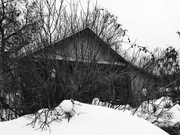 Старый заброшенный дом с разбитым окном на фоне снега зимой — стоковое фото