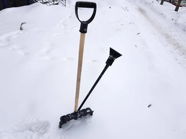 Снежная лопата и ледоруб зимой застряли в снегу. — стоковое фото