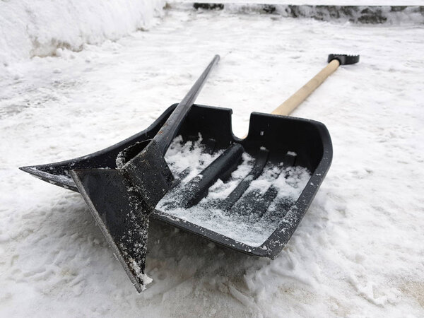 Snow shovel and ice ax lie on the snow in winter