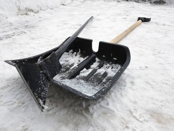 Снежная лопата и ледоруб зимой лежат на снегу — стоковое фото