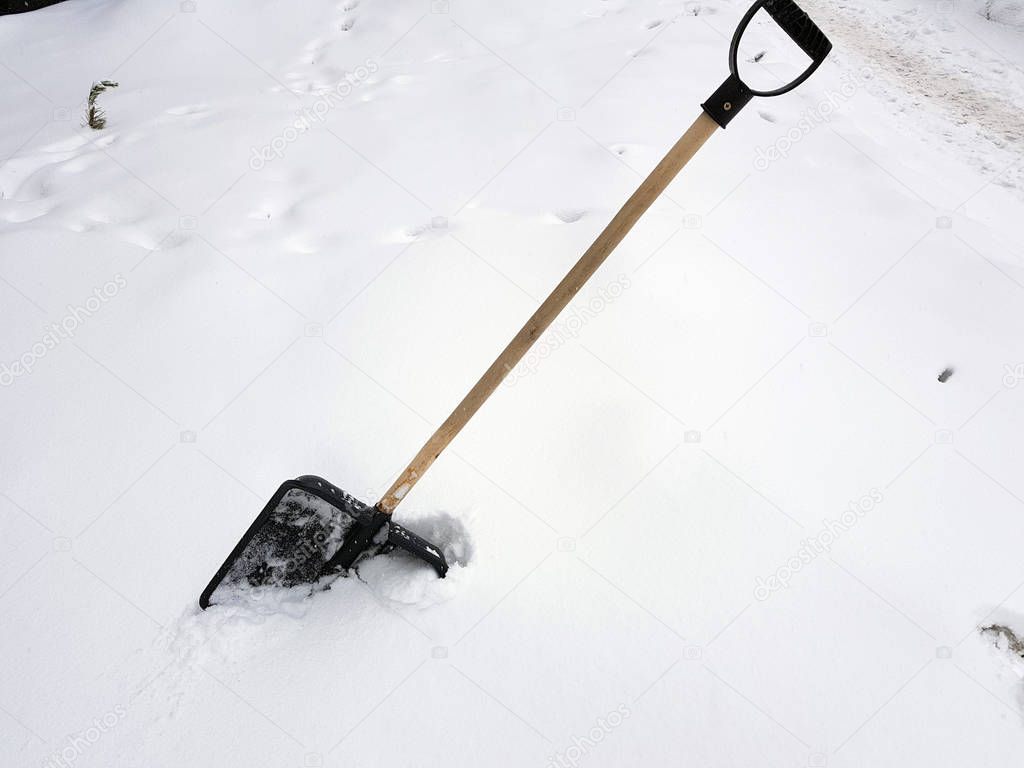 Snow shovel and ice ax stuck in the snow in winter