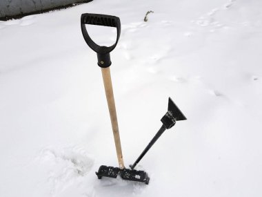 Kar küreği ve buz ax kışın karda sıkışmış