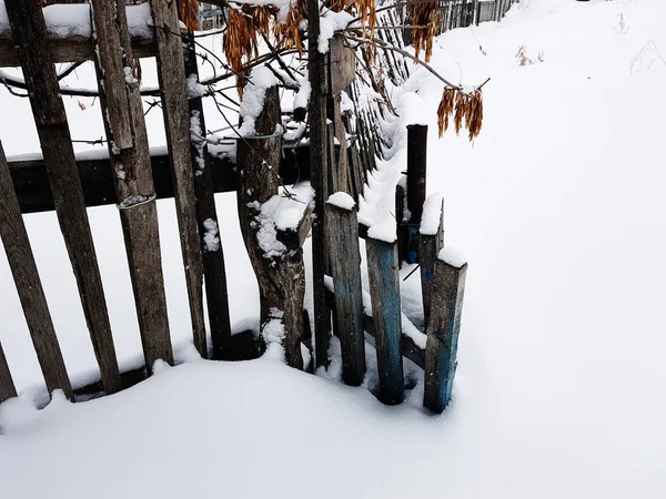 Bella vecchia recinzione di legno sullo sfondo della neve in inverno — Foto Stock