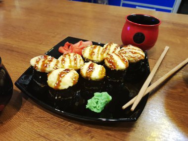 Güzel lezzetli soya sosu ve yemek çubukları ile siyah bir plaka üzerinde rulo