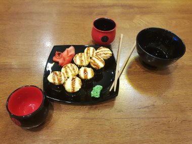 Güzel lezzetli soya sosu ve yemek çubukları ile siyah bir plaka üzerinde rulo