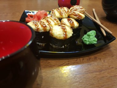 Güzel lezzetli soya sosu ve yemek çubukları ile siyah bir plaka üzerinde rulo