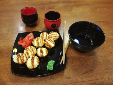 Güzel lezzetli soya sosu ve yemek çubukları ile siyah bir plaka üzerinde rulo