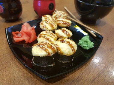 Güzel lezzetli soya sosu ve yemek çubukları ile siyah bir plaka üzerinde rulo