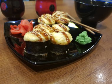 Güzel lezzetli soya sosu ve yemek çubukları ile siyah bir plaka üzerinde rulo