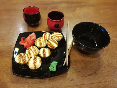 Güzel lezzetli soya sosu ve yemek çubukları ile siyah bir plaka üzerinde rulo