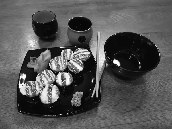 Hermosos rollos sabrosos en un plato negro con salsa de soja y palillos —  Fotos de Stock