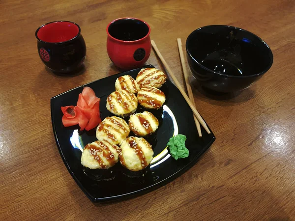 Красивые вкусные роллы на черной тарелке с соевым соусом и палочками для еды — стоковое фото