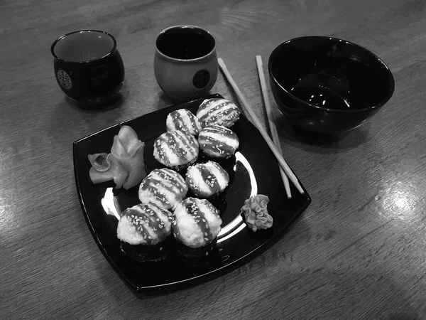 Güzel lezzetli soya sosu ve yemek çubukları ile siyah bir plaka üzerinde rulo — Stok fotoğraf