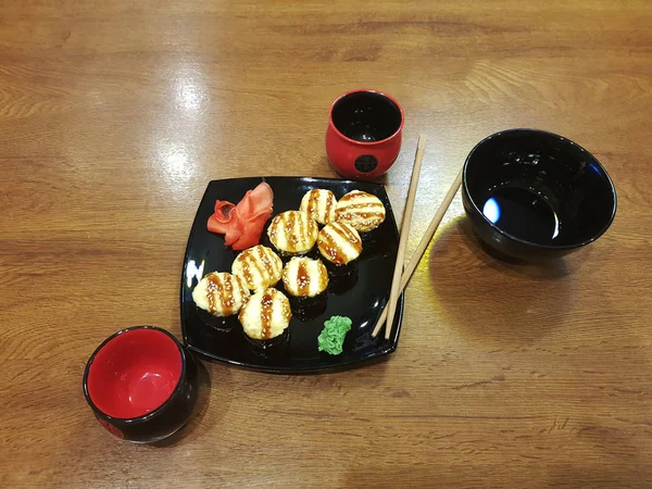 Красиві смачні рулети на чорній тарілці з соєвим соусом та паличками — стокове фото