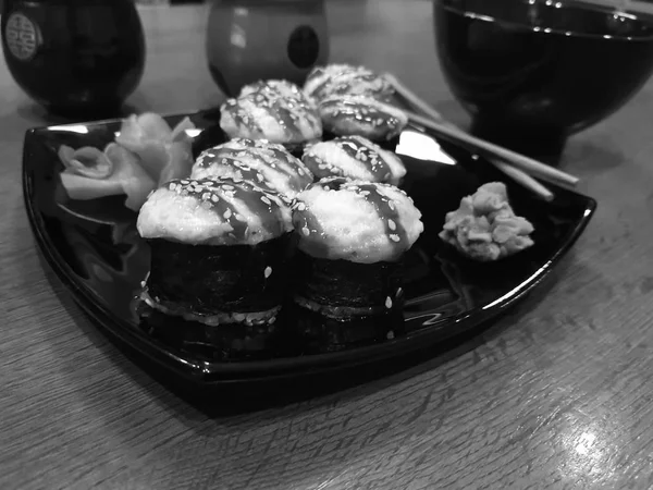 Mooie lekkere broodjes op een zwarte plaat met sojasaus en eetstokjes — Stockfoto