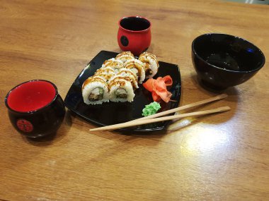 Güzel lezzetli soya sosu ve yemek çubukları ile siyah bir plaka üzerinde rulo