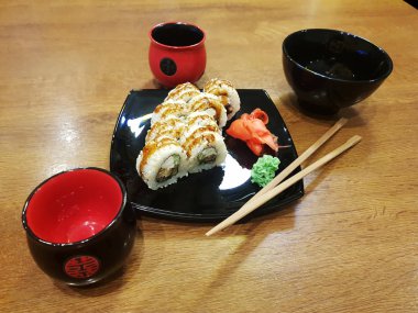 Güzel lezzetli soya sosu ve yemek çubukları ile siyah bir plaka üzerinde rulo