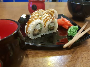 Güzel lezzetli soya sosu ve yemek çubukları ile siyah bir plaka üzerinde rulo