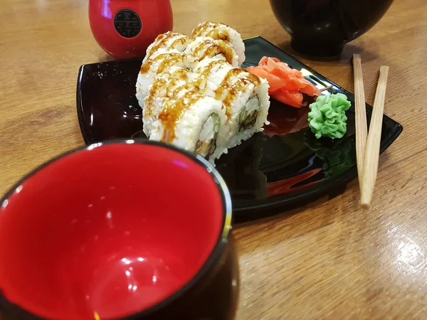 Güzel lezzetli soya sosu ve yemek çubukları ile siyah bir plaka üzerinde rulo