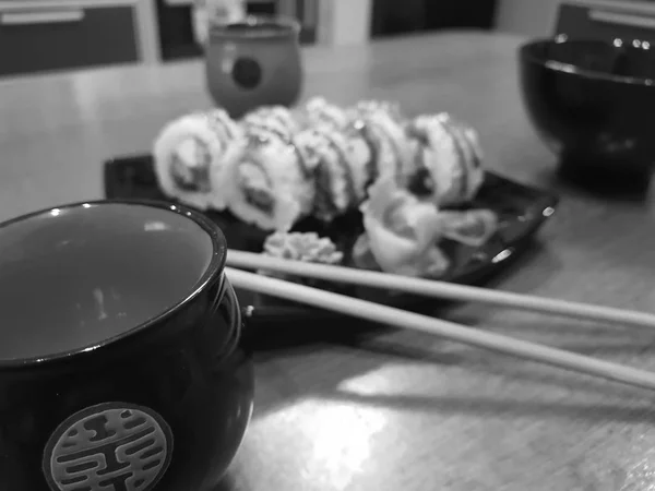 Beautiful tasty rolls on a black plate with soy sauce and chopsticks — Stock Photo, Image