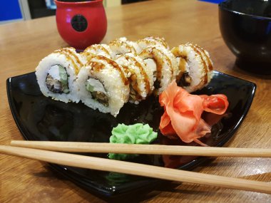 Güzel lezzetli soya sosu ve yemek çubukları ile siyah bir plaka üzerinde rulo