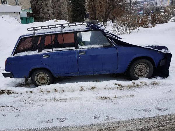 Mooie oude auto met een bekleding op de kap in de sneeuw — Stockfoto