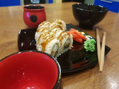 Güzel lezzetli soya sosu ve yemek çubukları ile siyah bir plaka üzerinde rulo