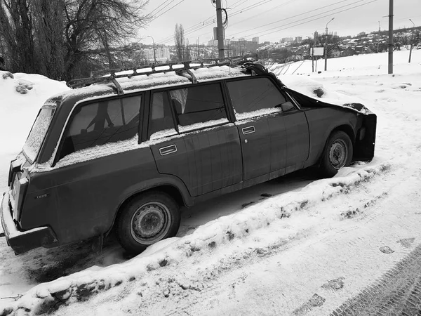 Старый автомобиль с крышкой на капоте в снегу — стоковое фото