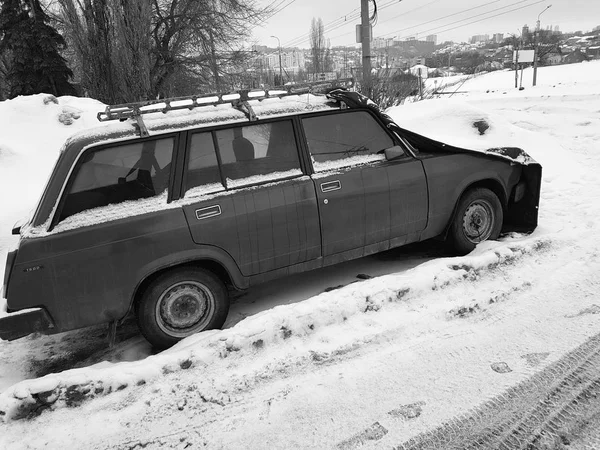 Старый автомобиль с крышкой на капоте в снегу — стоковое фото